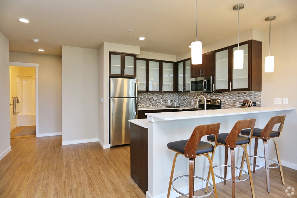 a kitchen with a bar and a stainless steel refrigerator