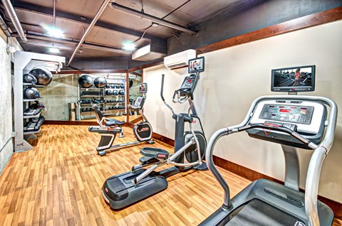 a gym with various machines and weights on a wooden floor