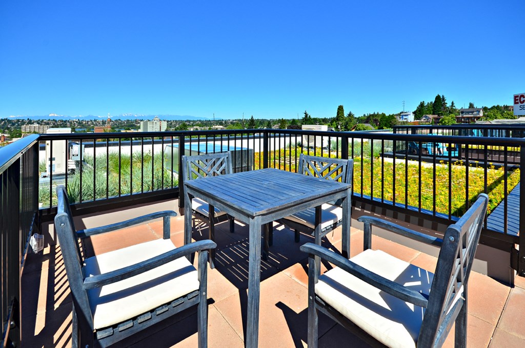 the balcony has a table and chairs and views of the city