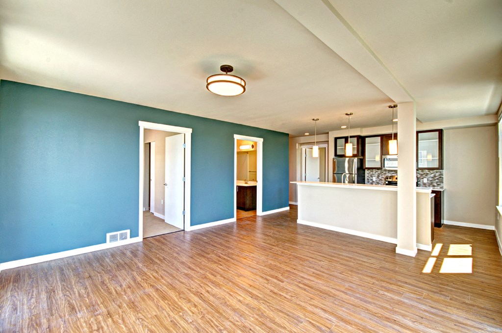 an empty living room and kitchen with a hard wood floor