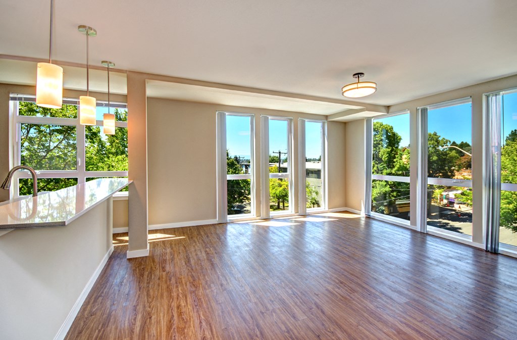 an empty living room with wood floors and large windows