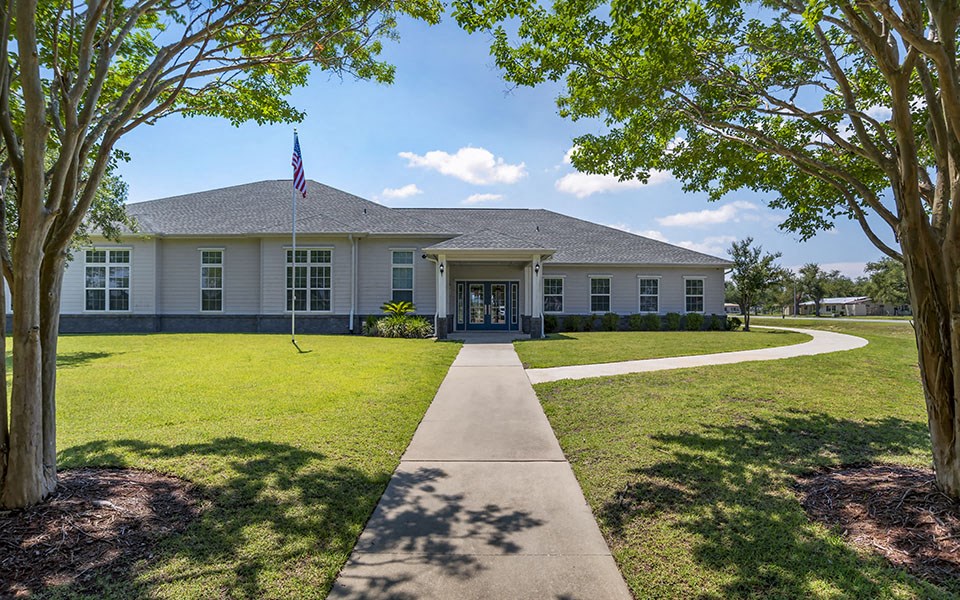 the front of a white building with a flag and a sidewalk