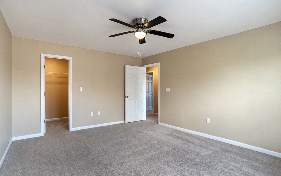 an empty living room with a ceiling fan