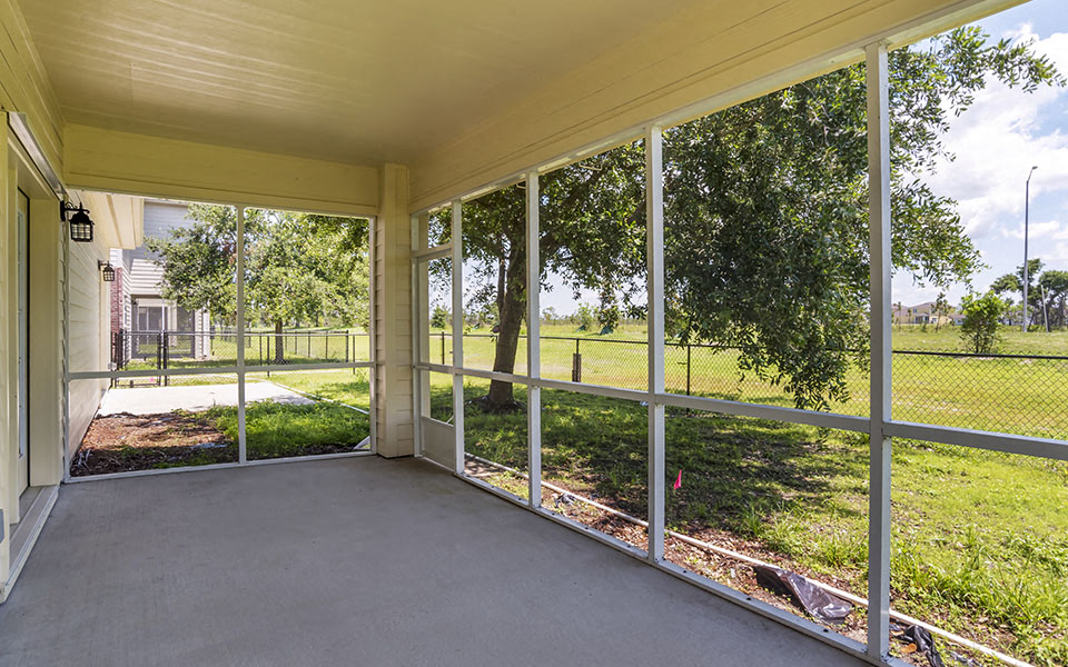 a large porch with large windows overlooking a grass field