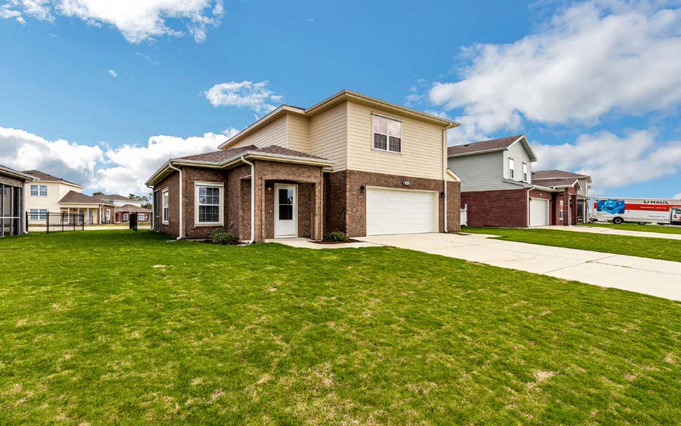 a house with a driveway and lawn in front of it