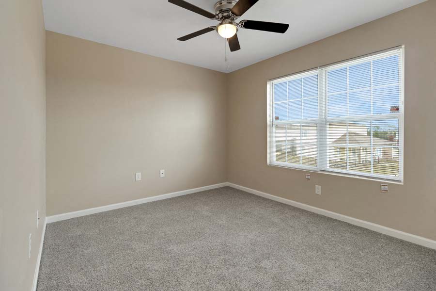 an empty bedroom with a ceiling fan and a window