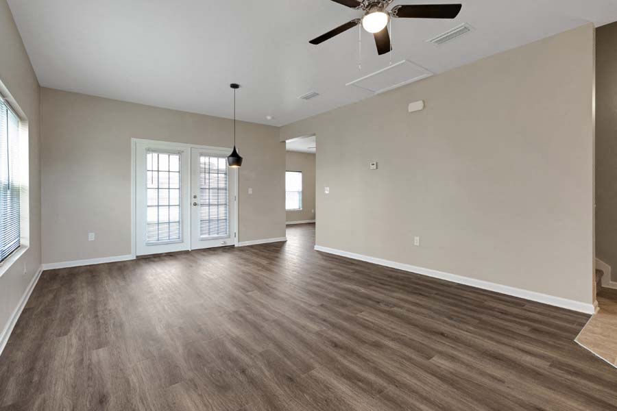an empty living room with a ceiling fan