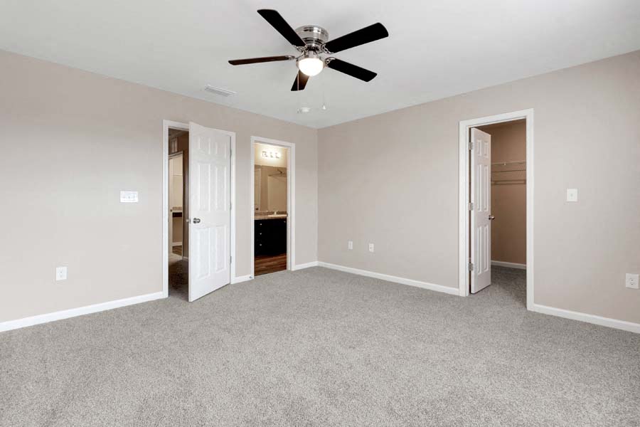 an empty living room with a ceiling fan