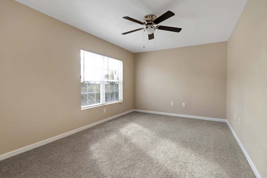 an empty living room with a ceiling fan and a window