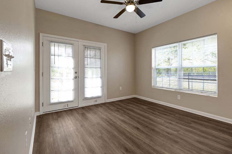 an empty living room with a ceiling fan and windows