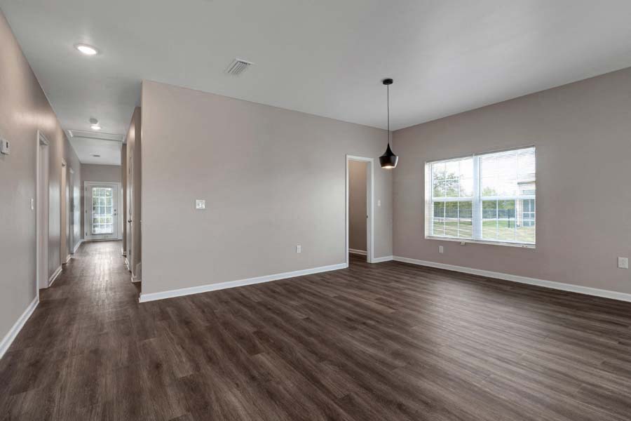 an empty living room with a large window and wood floors