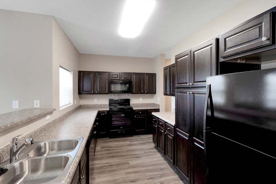 a large kitchen with black appliances and a sink