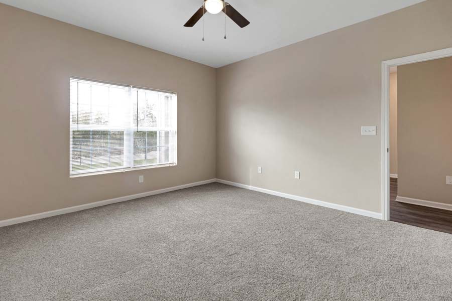 an empty room with a window and a ceiling fan