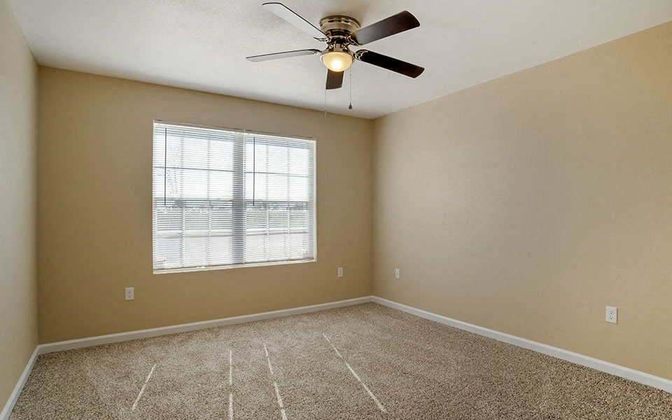 an empty room with a ceiling fan and a window