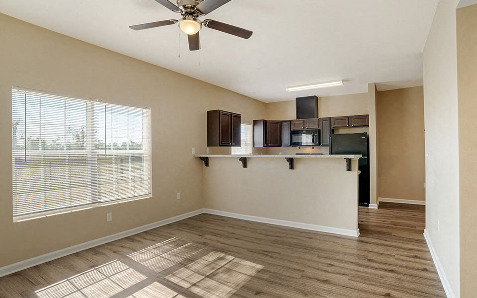 an empty living room with a ceiling fan and a window