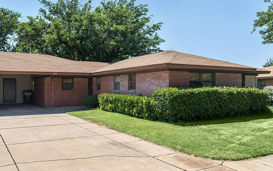 a brick house with a driveway and a lawn