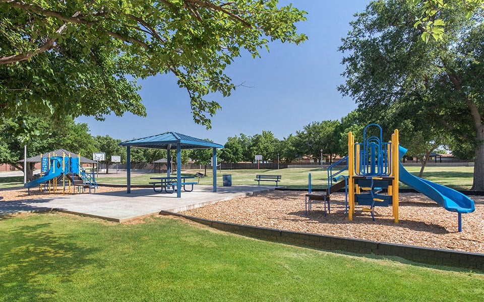 playgrounds and picnic tables in a park with trees