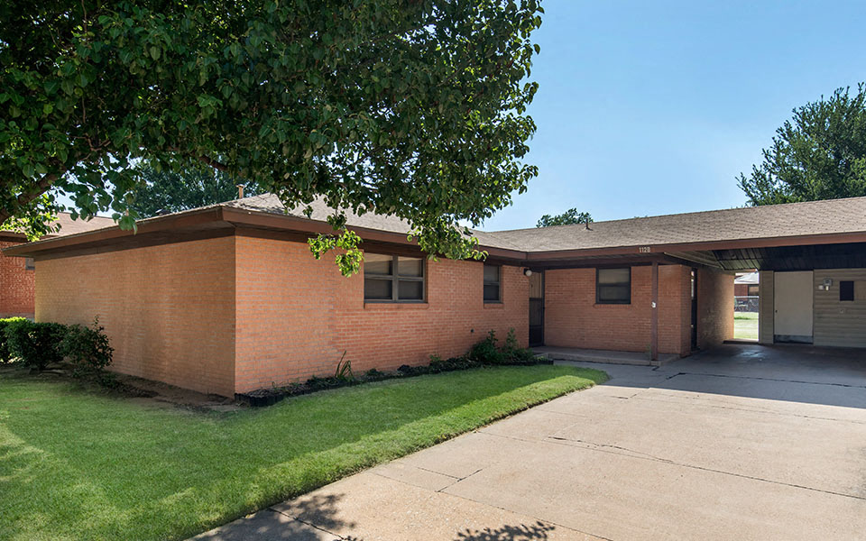 a brick house with a sidewalk and a tree