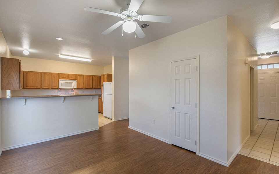 an empty living room and kitchen with a ceiling fan