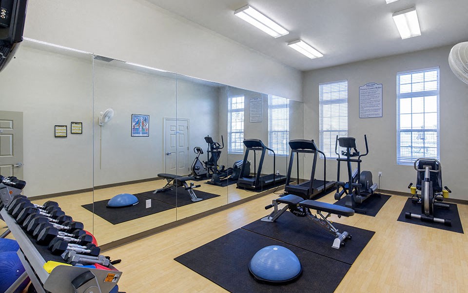 a gym with exercise equipment and mirrors in a large room