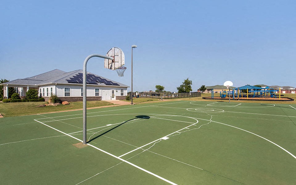 a basketball court with a playground and a house