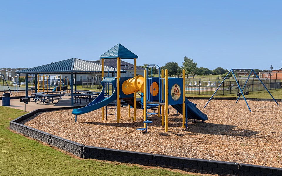 a playground with a blue and yellow swing set
