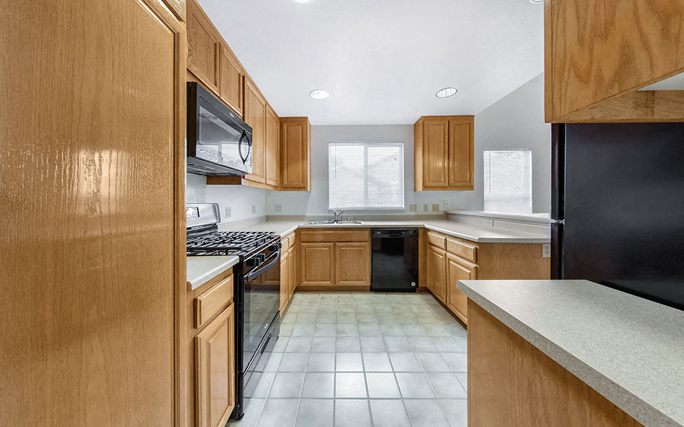 a kitchen with wooden cabinets and a black refrigerator