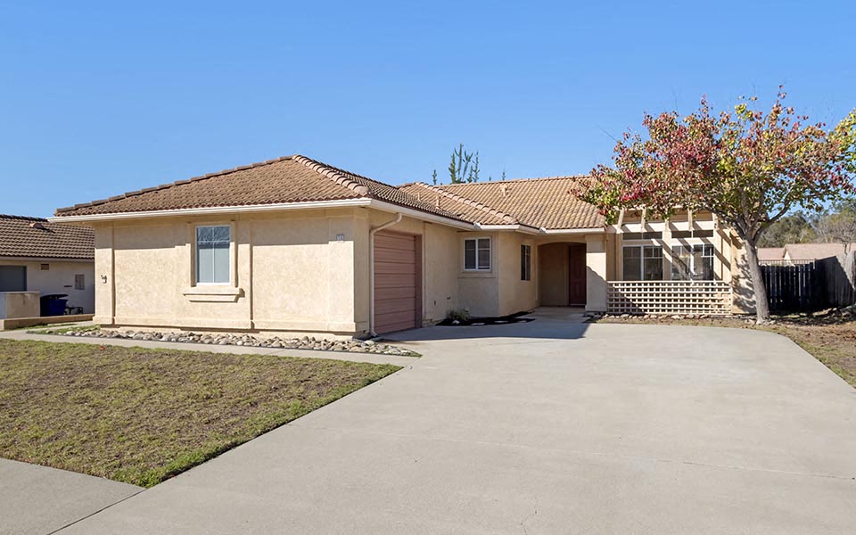a house with a driveway and a tree in front of it
