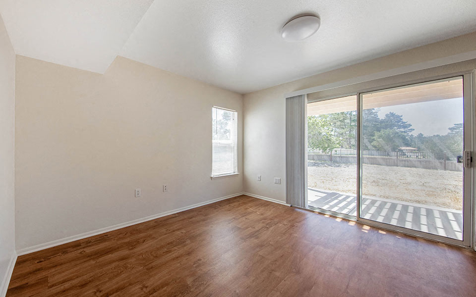 an empty living room with a sliding glass door to a patio