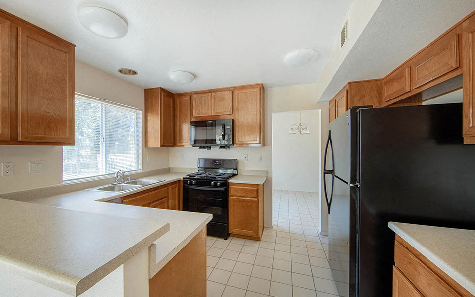 a kitchen with wooden cabinets and a black refrigerator
