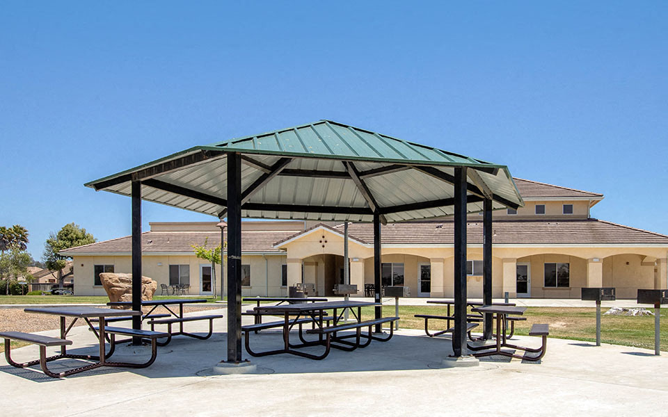 a pavilion with picnic tables in front of a building