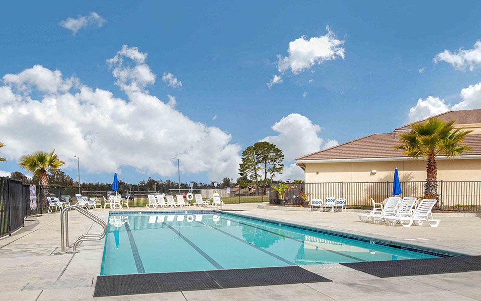 a swimming pool with chairs and a building in the background