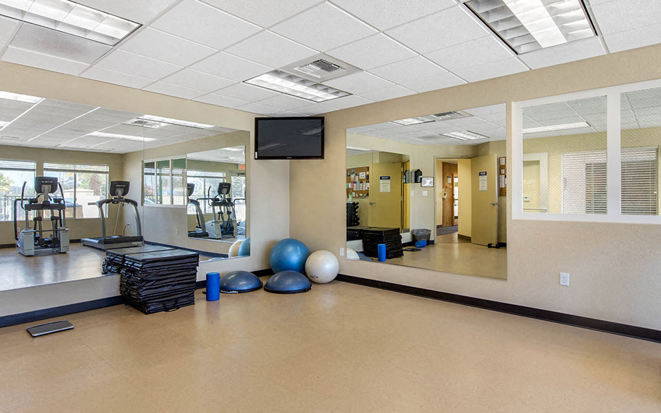 a fitness room with weights and cardio equipment on the floor