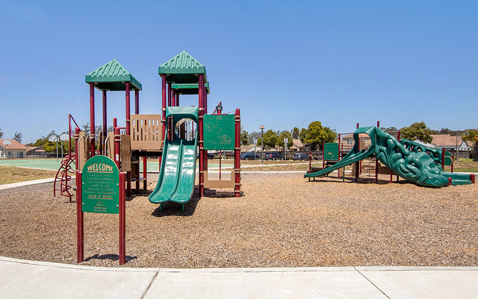 a playground with a mix of play equipment in a park