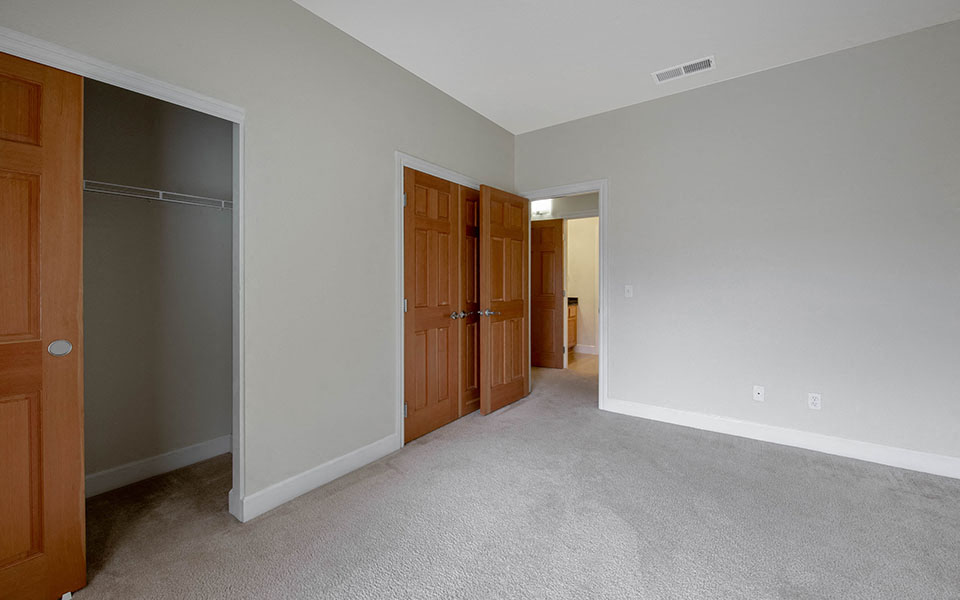 a empty living room with two doors and a closet
