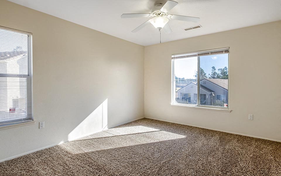 an empty bedroom with a ceiling fan and a window