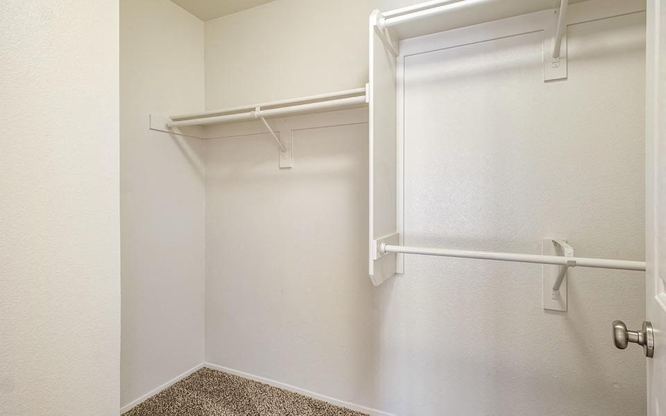 a walk in closet with a white wall and a white
