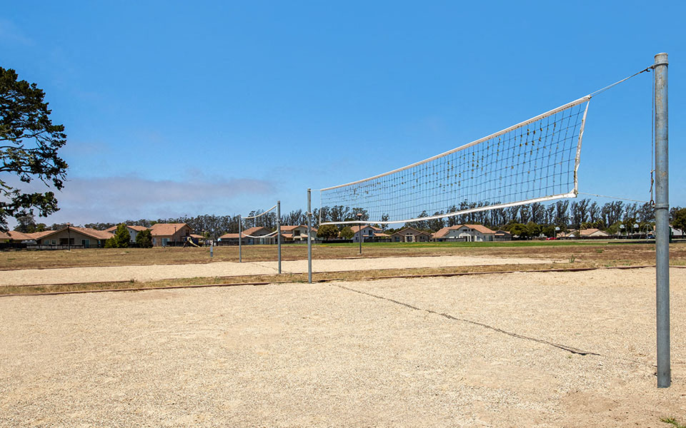 a volleyball court in a dirt field with houses in the background