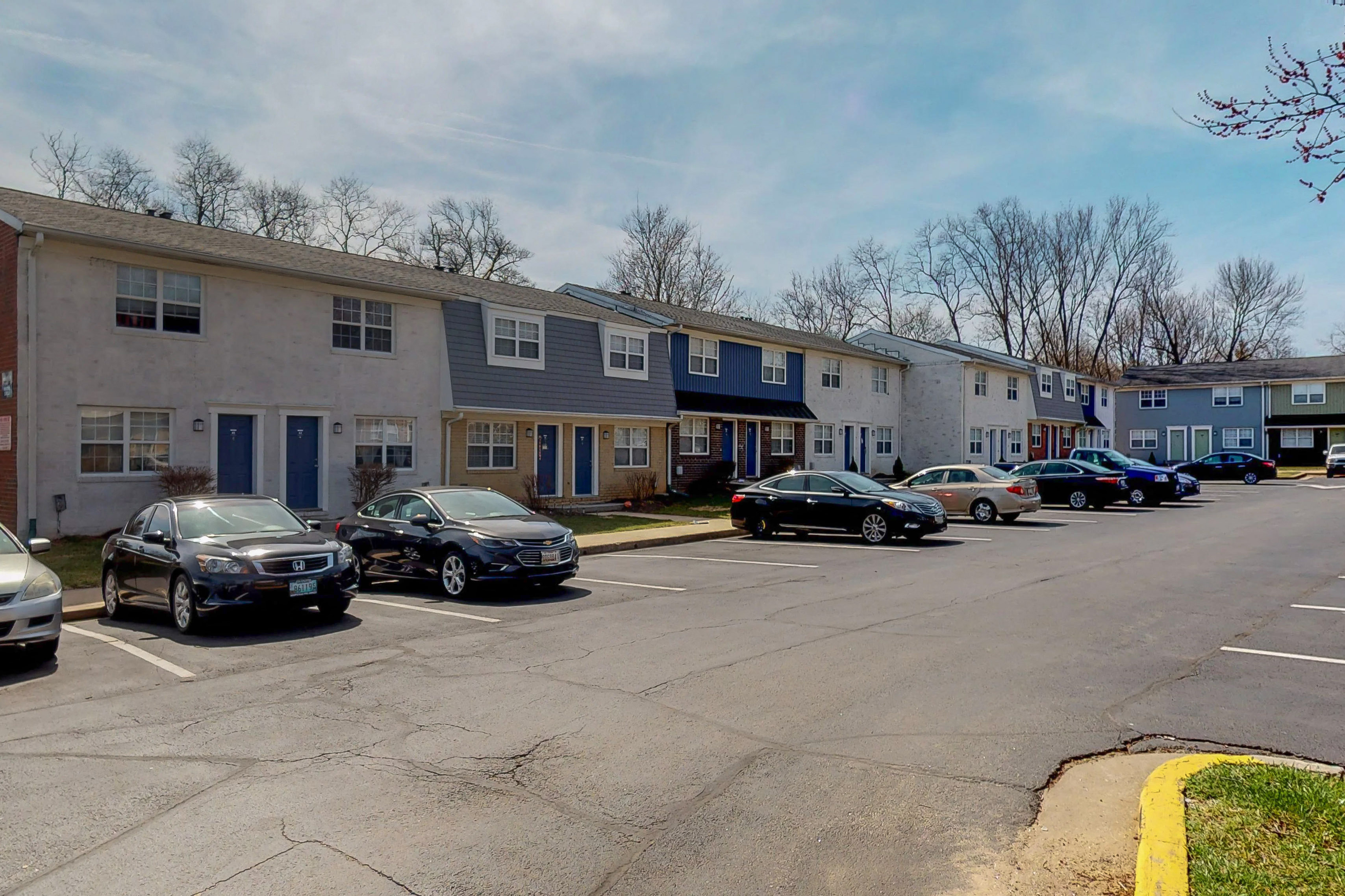 a parking lot filled with cars in front of apartment buildings