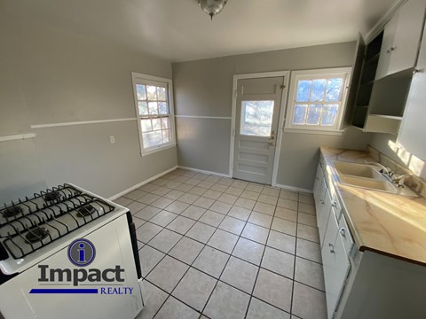 A kitchen with Impact Realty logo on a gas stove.