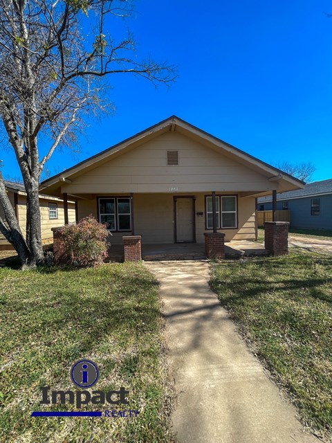 A house with Impact Realty logo on the grass.