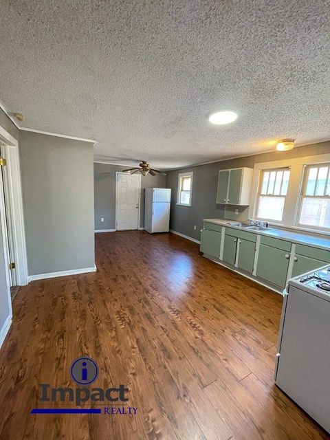 A kitchen with wood floors and a refrigerator.