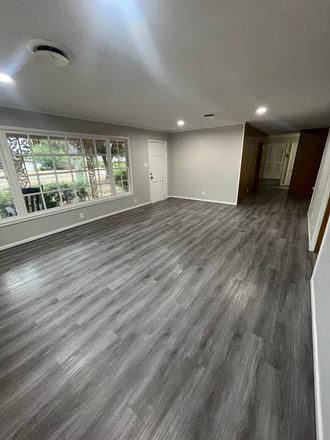 an empty living room with vinyl flooring and a large window
