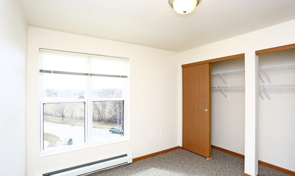 A room with a brown door and a window with blinds.