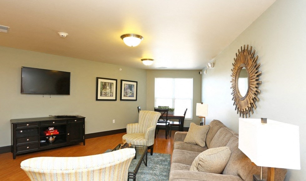 Community room with a television, a chair, a couch, and a mirror.