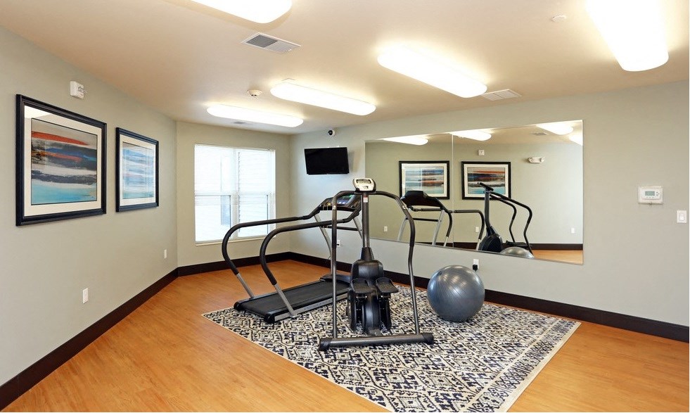 Fitness room with a treadmill, exercise ball, and mirrors.
