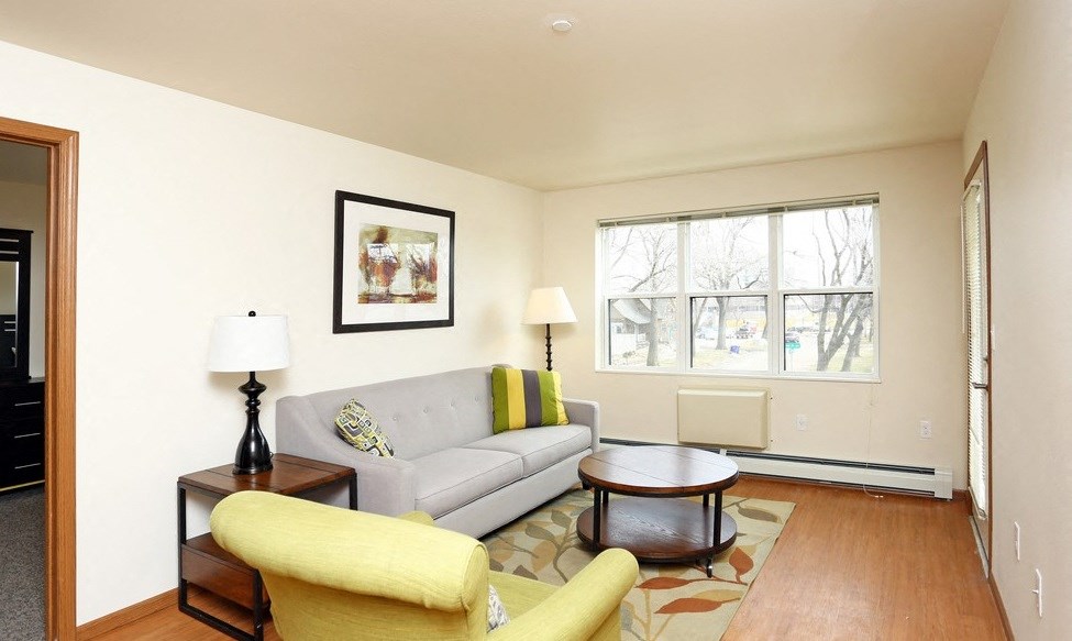 A living room with a grey couch, yellow chair, and a lamp on a side table.