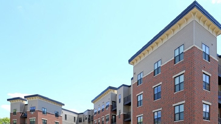 A large apartment complex with cars parked in front.