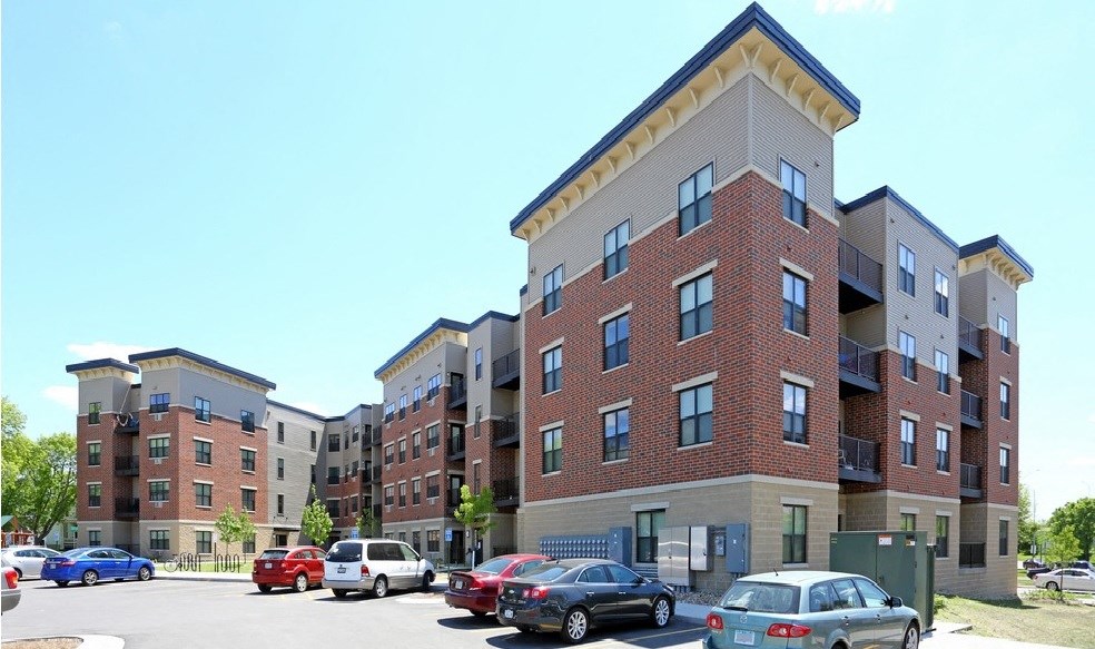 an apartment building with cars parked in a parking lot