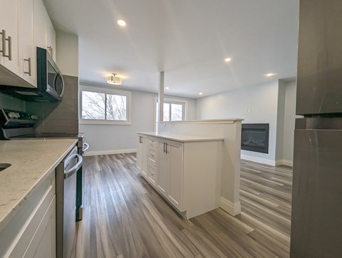 A kitchen with white cabinets and a wooden floor.